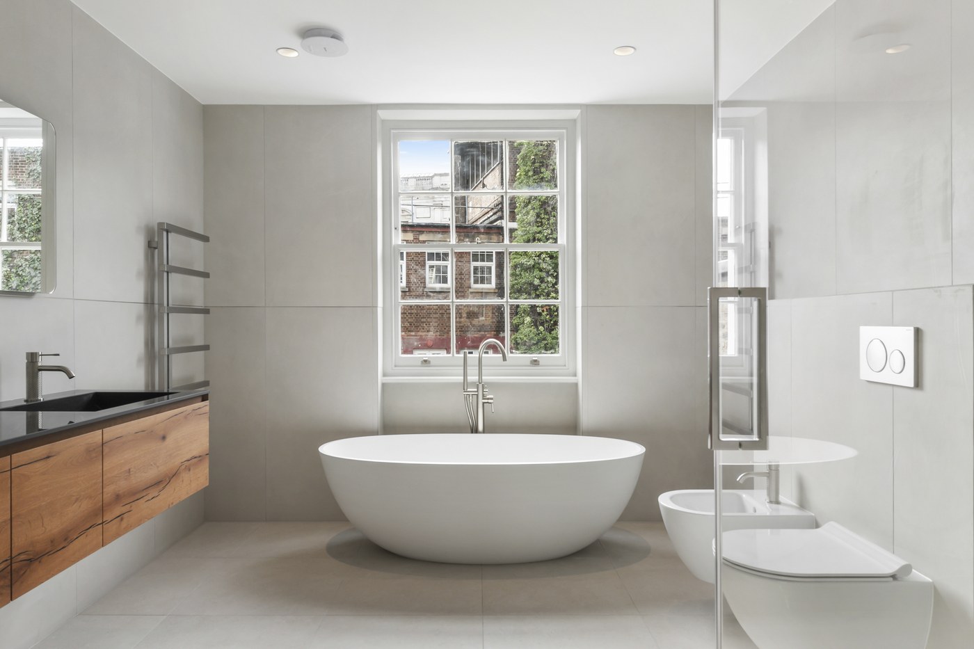 Bathroom at Brompton Square with a freestanding bath, timber vanity and glazed shower screen