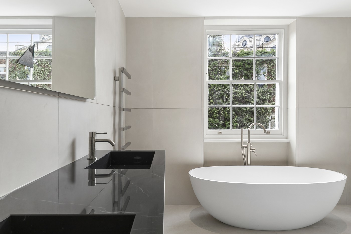 Bathroom at Brompton Square with a dark stone vanity, freestanding bath and heated towel rail