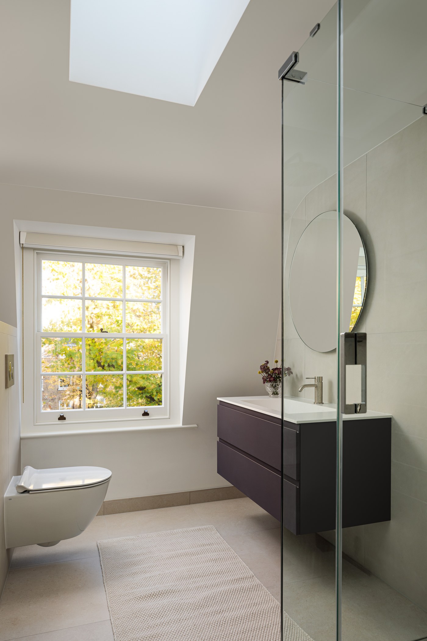 Bathroom vanity and round mirror at Brompton Square, beside the retained sash window