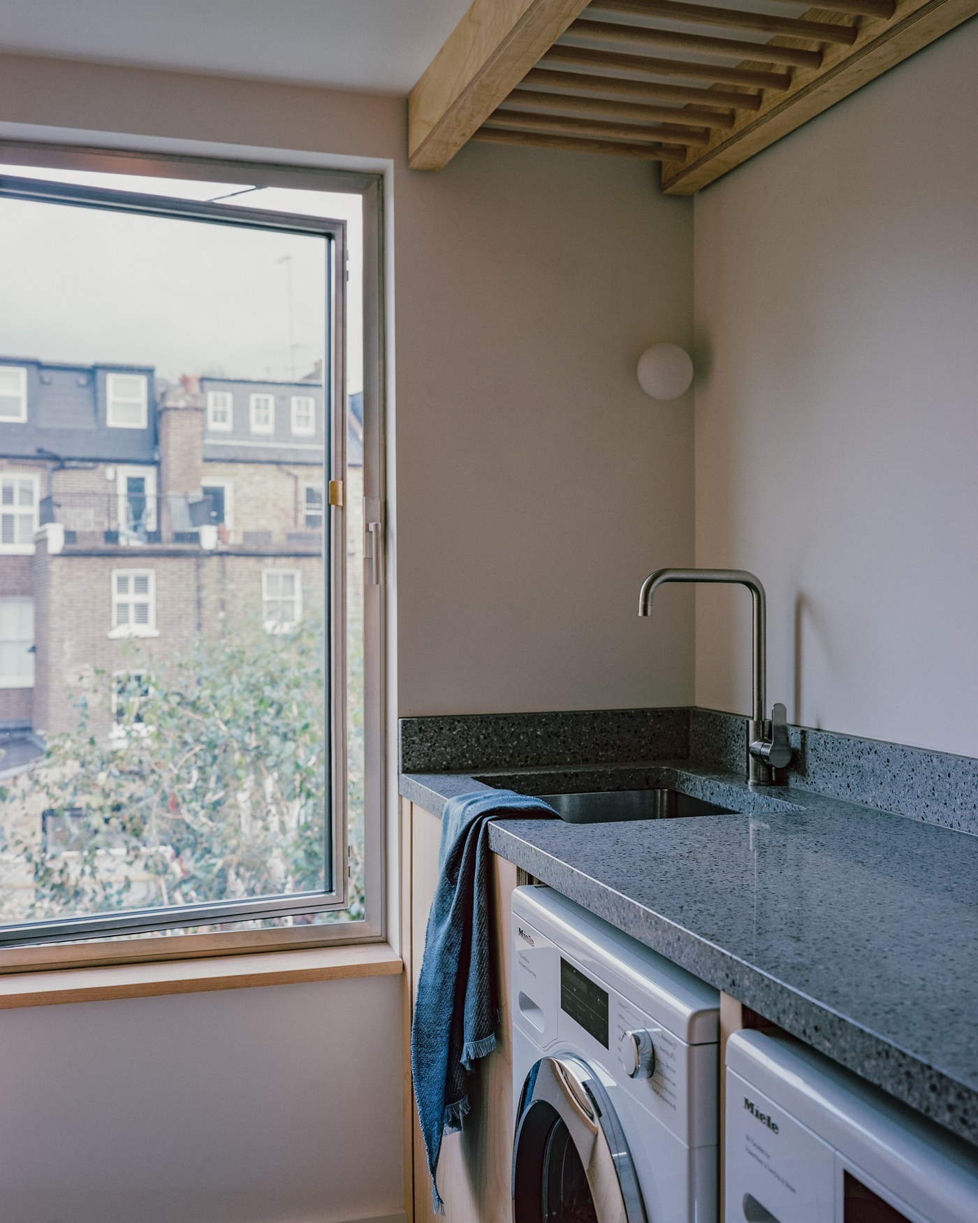 Caithness Road W14 — utility room with a stone worktop, washing machine and dryer, under exposed timber joists