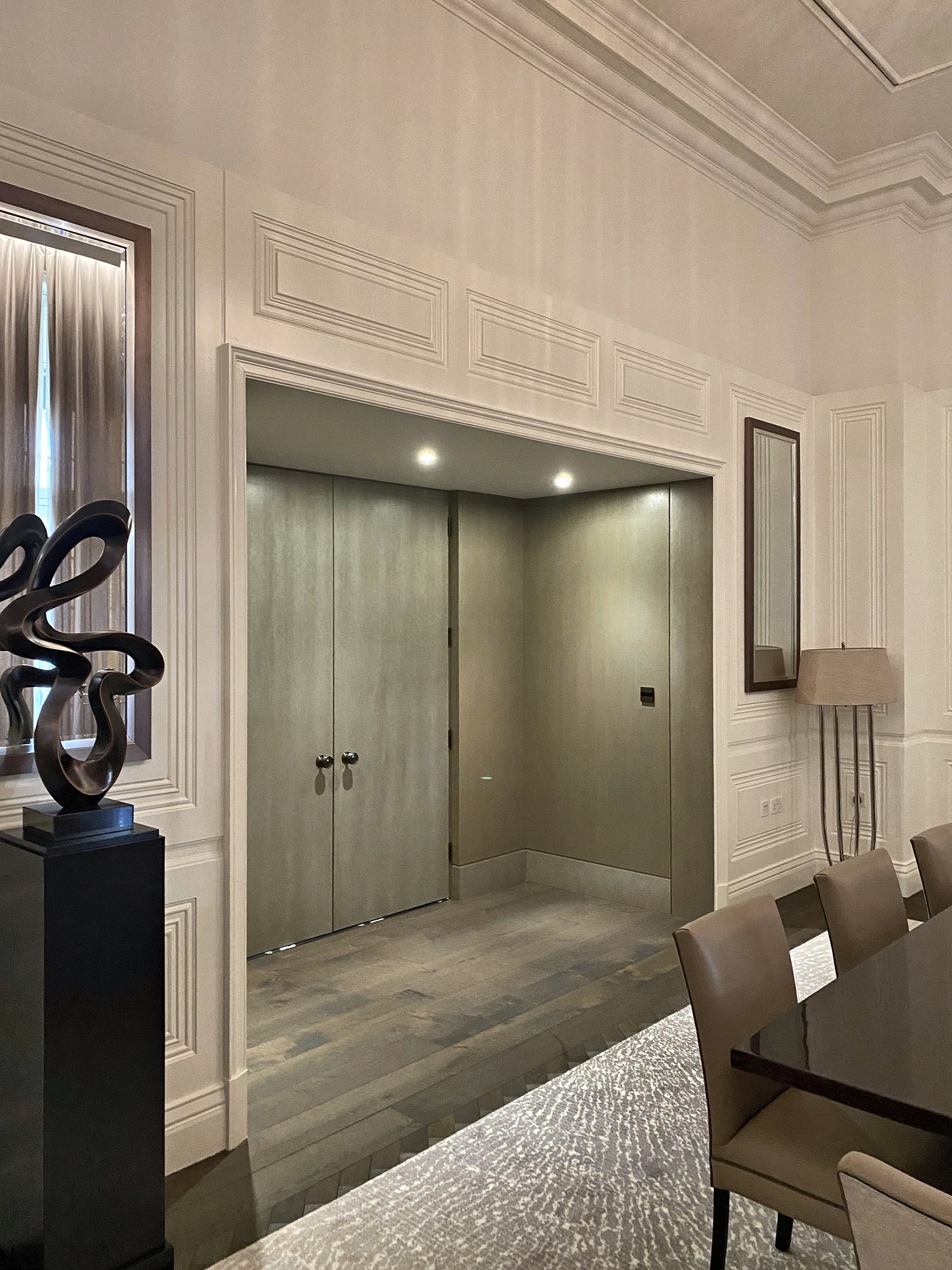 Entrance hall at Connaught Place with timber double doors and storage concealed within the panelling